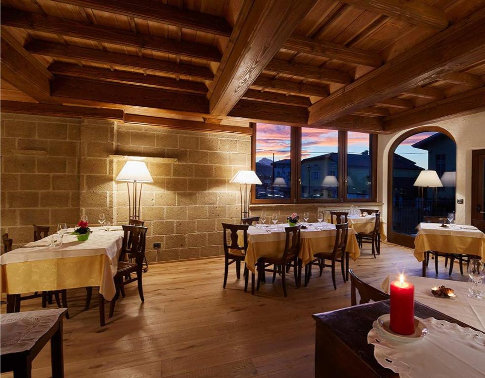 uma sala de jantar com mesas, cadeiras e janelas em Hotel Ristorante Da Politano em Boves