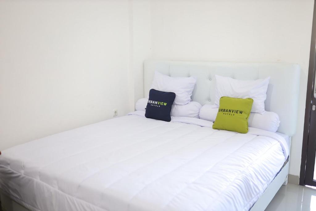 a white bed with two pillows on it at Urbanview Hotel Eropa Maros near Sultan Hasanuddin Airport by RedDoorz in Maros