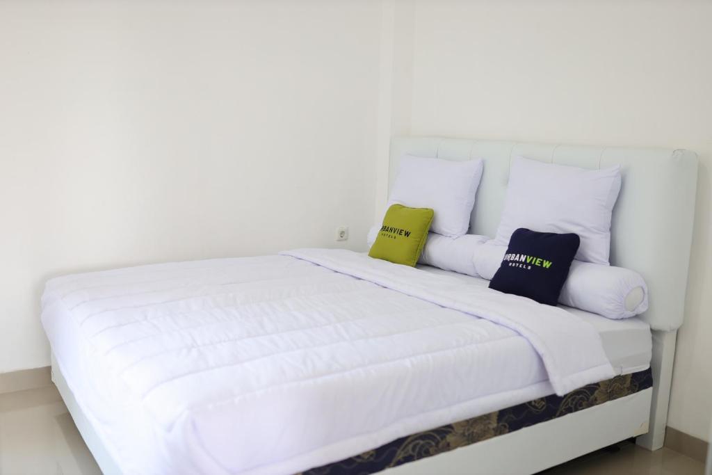 a white bed with three pillows on it at Urbanview Hotel Eropa Maros Near Sultan Hasanuddin Airport in Maros