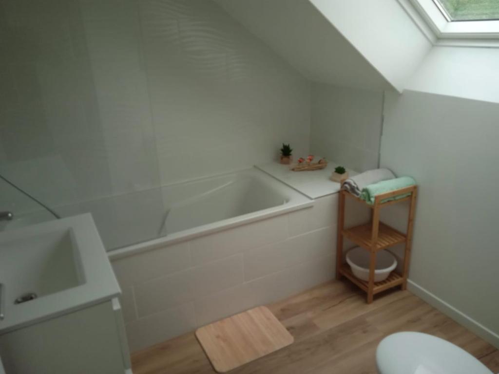 a white bathroom with a tub and a toilet at Gîte le Rouge Gorge de Brocéliande in Beignon