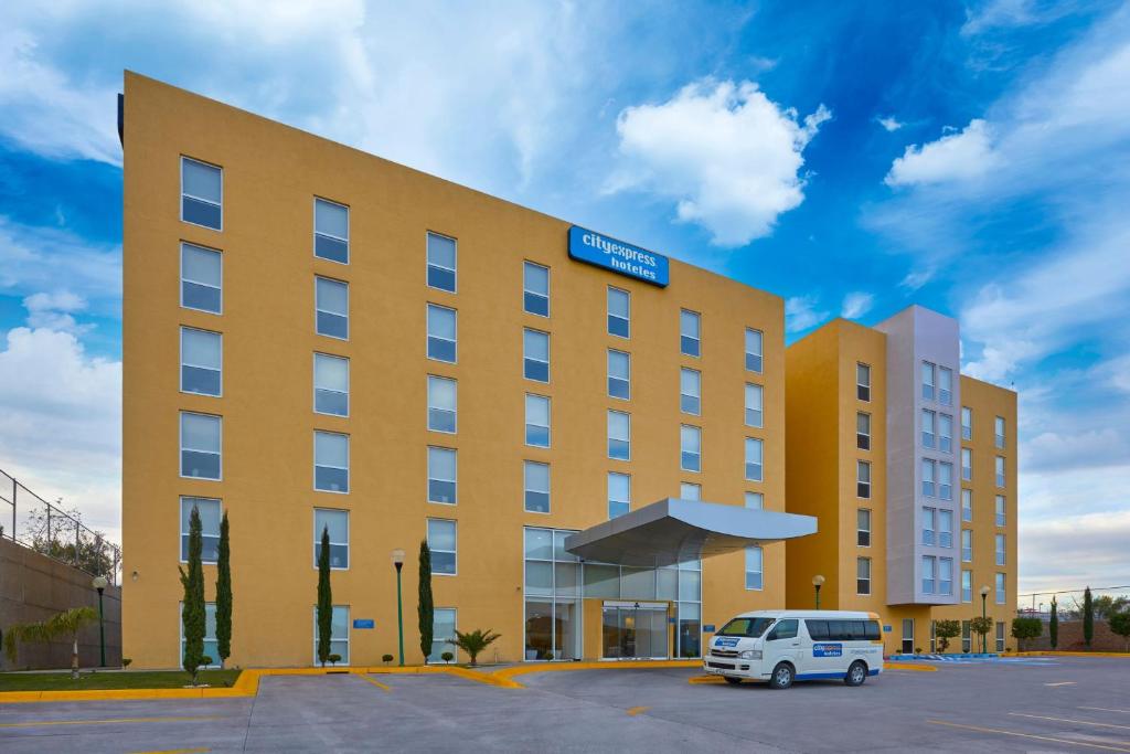 um edifício amarelo com uma carrinha branca estacionada num parque de estacionamento em City Express by Marriott Nogales em Nogales