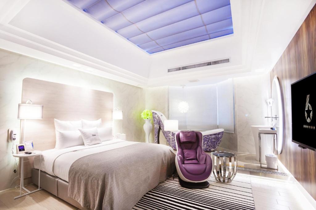 1 dormitorio con 1 cama grande con silla morada en Six Star Motel-Taoyuan en Taoyuan