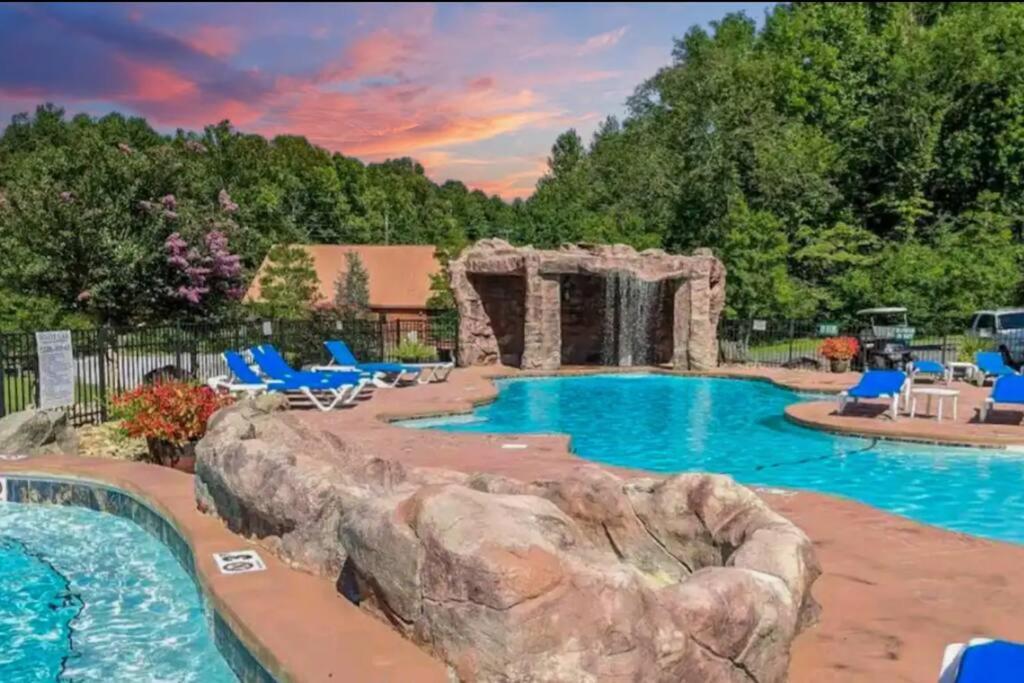 ein Pool in einem Resort mit einem Felsen in der Mitte in der Unterkunft LUXURY 4BR Cabin in Gatlinburg with Views Hot Tub with Private Deck Game Room Most Popular Coffee Bar Perfect for Family Getaway Tennis Courts Infant Crib and Karaoke System in Gatlinburg