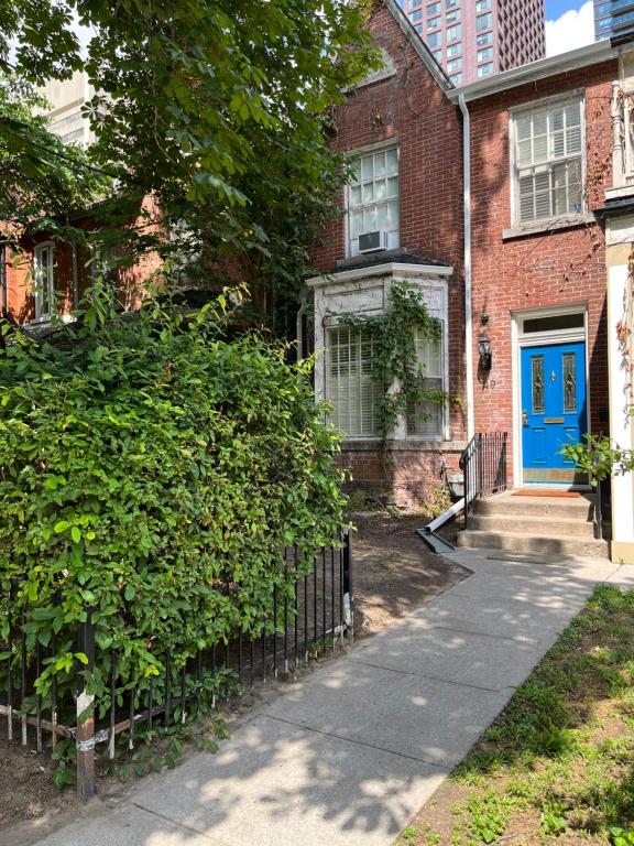 a brick house with a blue door and a sidewalk at 49 Hostel in Toronto