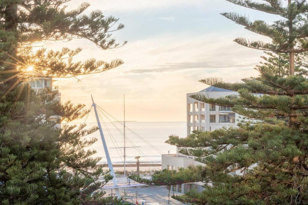 a sailboat in a marina with a building and trees at SUNSET GETAWAY GLENELG in Glenelg