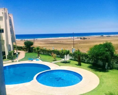 ein großer blauer Pool neben einem Strand in der Unterkunft Piso vistas al mar in Asilah