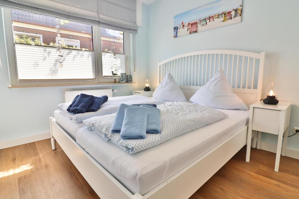 a bedroom with a white bed with blue towels on it at Anker in Langeoog