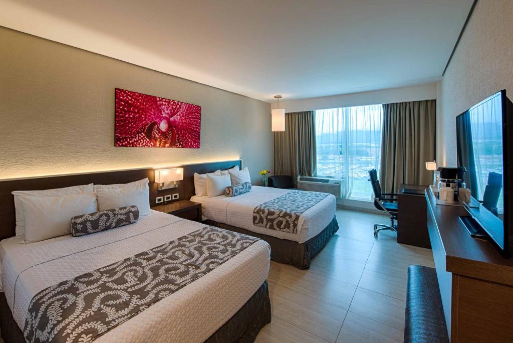 a hotel room with two beds and a flat screen tv at Crowne Plaza Airport by IHG in Tocumen