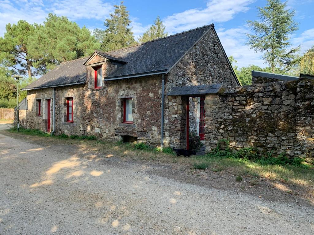 an old stone building with red windows and a stone wall at Le moulin du château in Blain