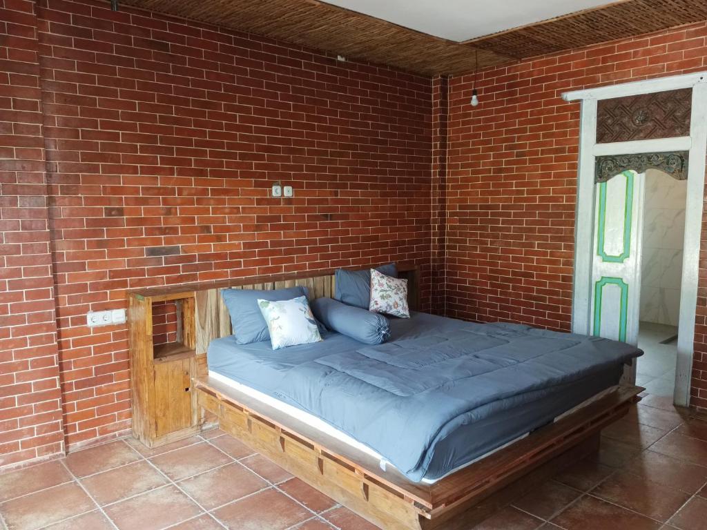 uma cama num quarto com paredes de tijolo e em Pondok isoke bunggalow em Banyuwangi