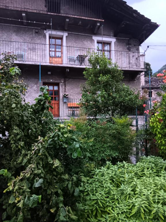 an old building with a red door and some bushes at La Casa Antica in Pont-Saint-Martin