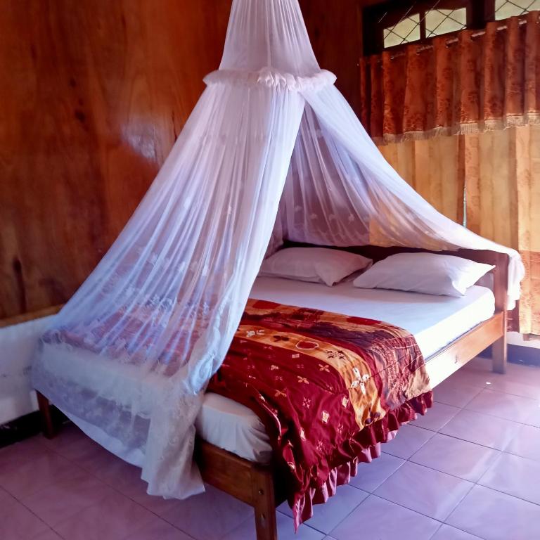 a bed with a mosquito net on top of it at WATUGANA BUNGALOW KELIMUTU in Kelimutu