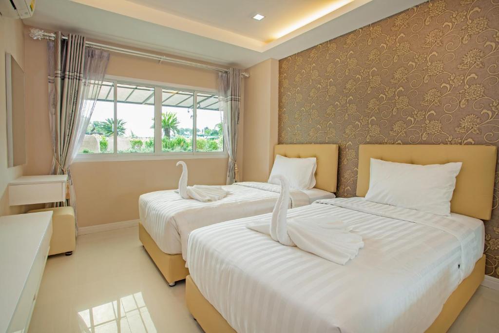 two beds in a room with a window at ROYAL GRAND PATTAYA in Nong Prue