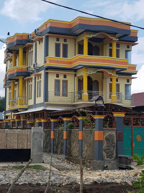 a large yellow and blue house with a fence at FIFAWIND HOTEL in Labuan Bajo