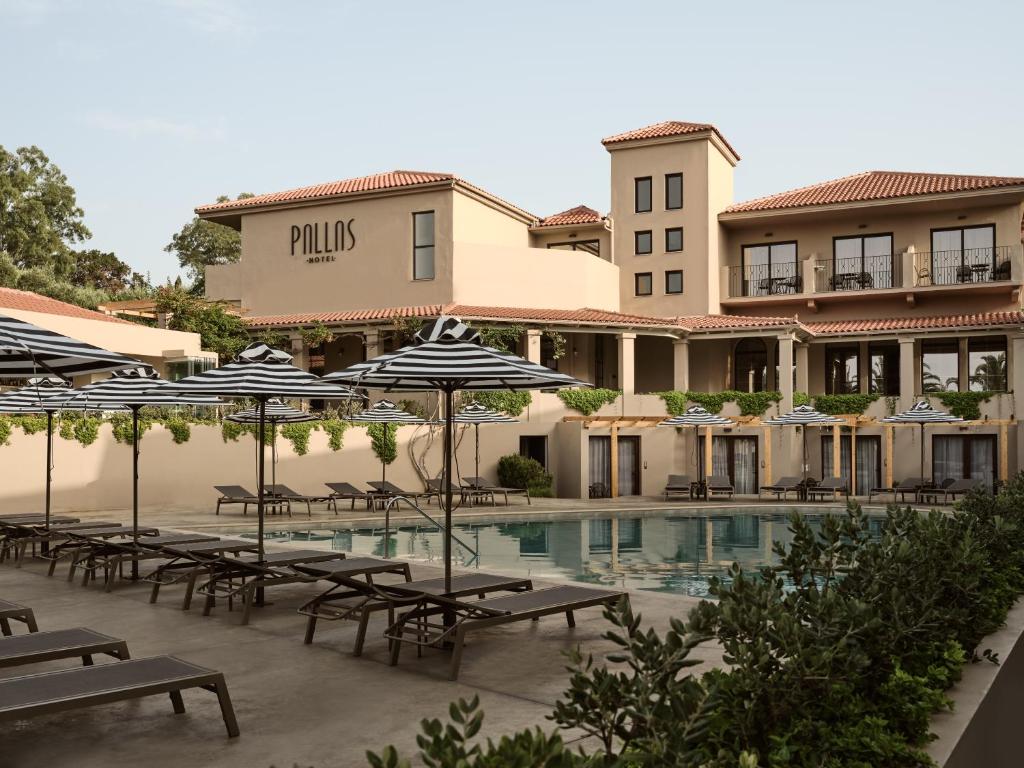 una piscina con mesas y sombrillas frente a un hotel en Hotel Pallas, en Laganas