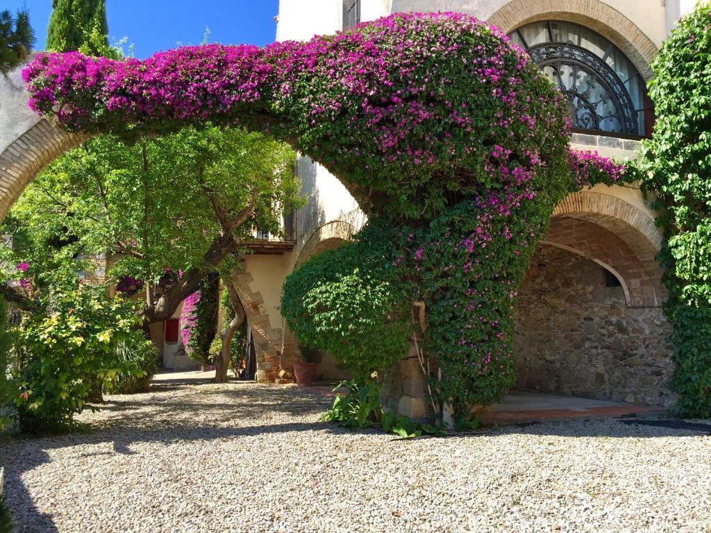 un arco con flores púrpuras en un edificio en Apartaments Can Gibert, en Castelló d'Empúries
