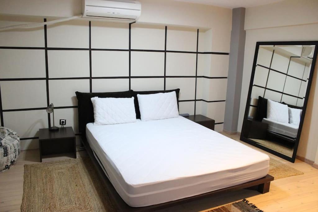1 dormitorio con 1 cama blanca grande y espejo en Modern Loft in the city center of Levadia, Greece en Levádeia