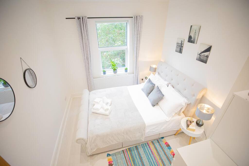 Habitación blanca con cama y ventana en Hammersmith Apollo 1 Bedroom Apartment, en Londres
