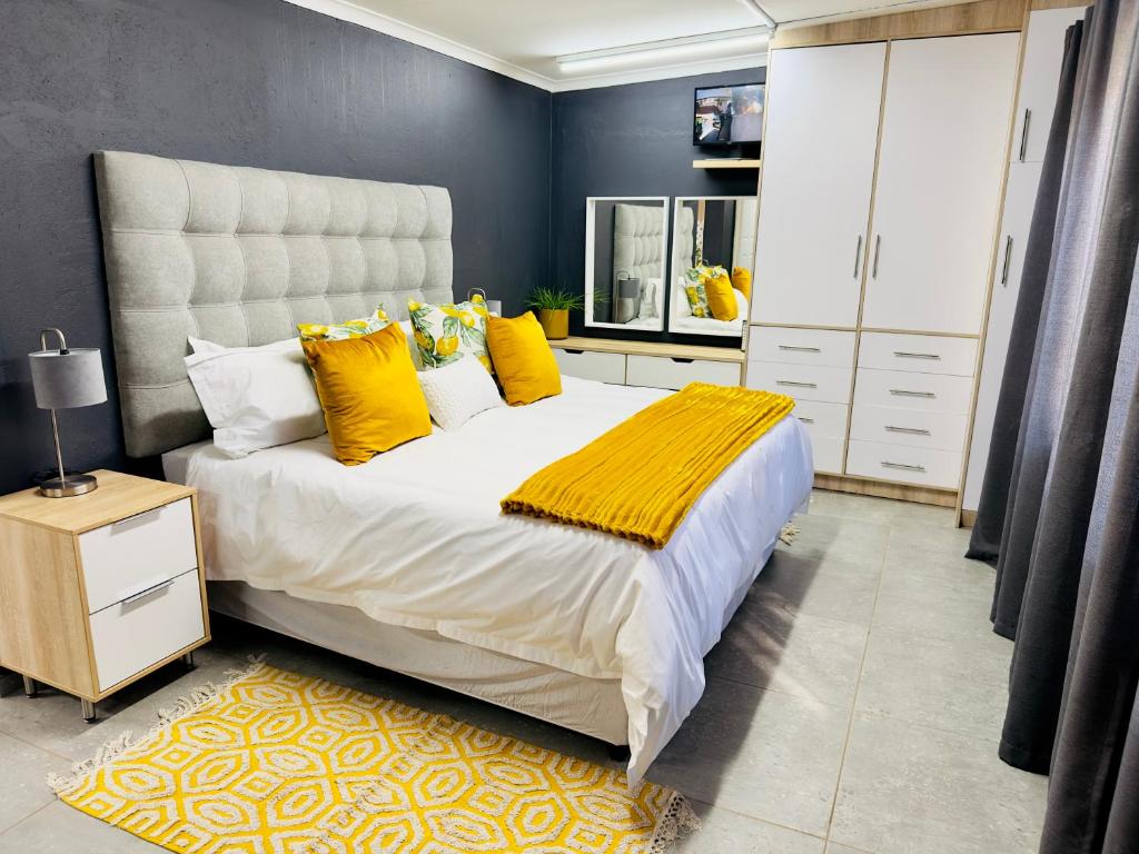 1 dormitorio con 1 cama grande con almohadas amarillas en Lemon Ivy Guesthouse, en Polokwane