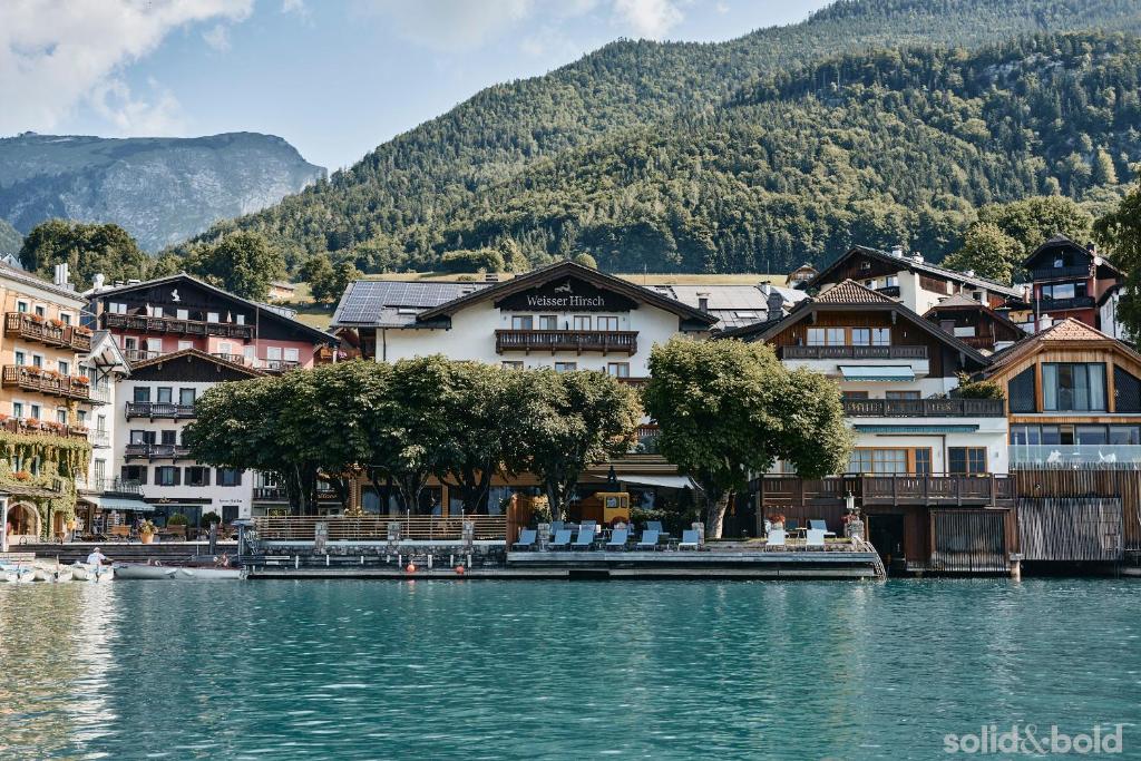 een groep gebouwen aan de oever van een meer bij Hotel Weisser Hirsch in St. Wolfgang