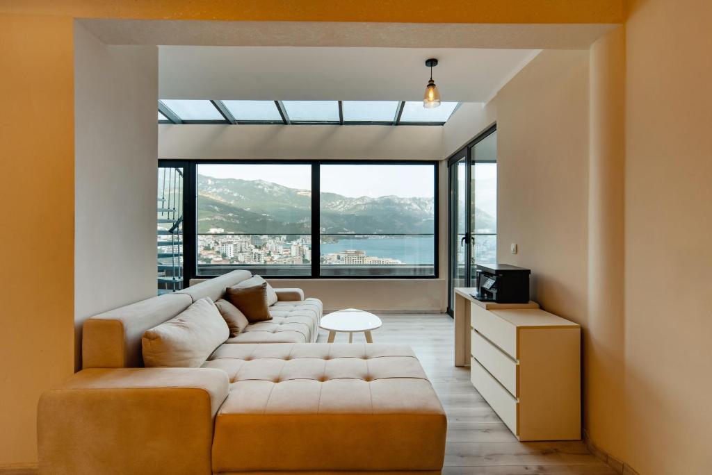 a living room with a large couch and large windows at Budva Gate Penthouse in Budva