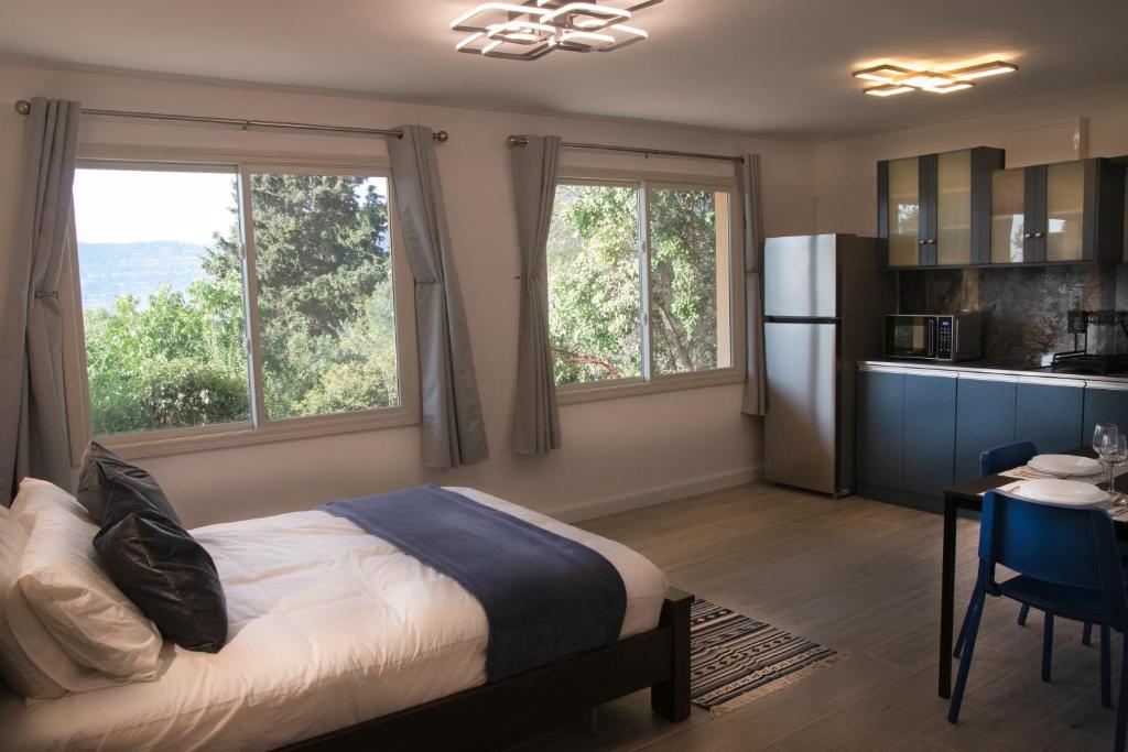 sypialnia z łóżkiem oraz kuchnia z oknami w obiekcie הבית ליד הבוסתן דירה לזוג w mieście Mikhmannim