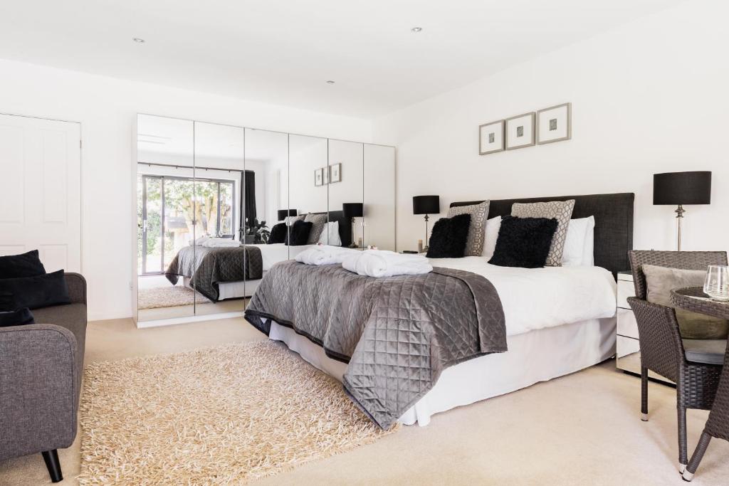 a white bedroom with two beds and a mirror at Boswenna in St Ives