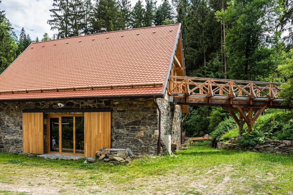 ein Steinhaus mit einer Holzbrücke darüber in der Unterkunft Stodola Ve Žlebě 