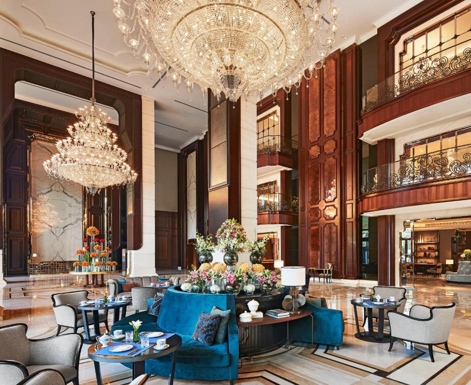 a lobby with chandeliers and tables and chairs at The Ritz-Carlton, Pune in Pune