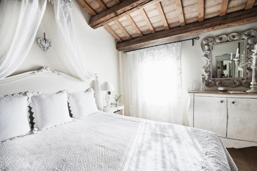 a white bedroom with a white bed and a mirror at Casina Le Conserve in Cesenatico