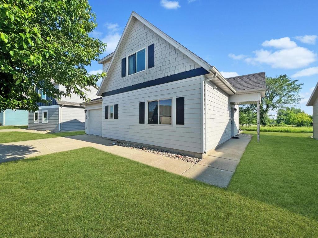 a white house with a grass yard at Bridges Bay Vacation Cabin 33 in Arnolds Park