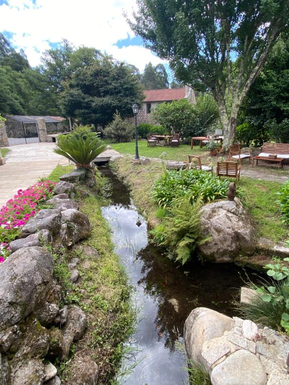 un arroyo en un jardín con rocas y flores en Entre Os Ríos - Casa Rural y Enoturismo, en Pobra do Caramiñal