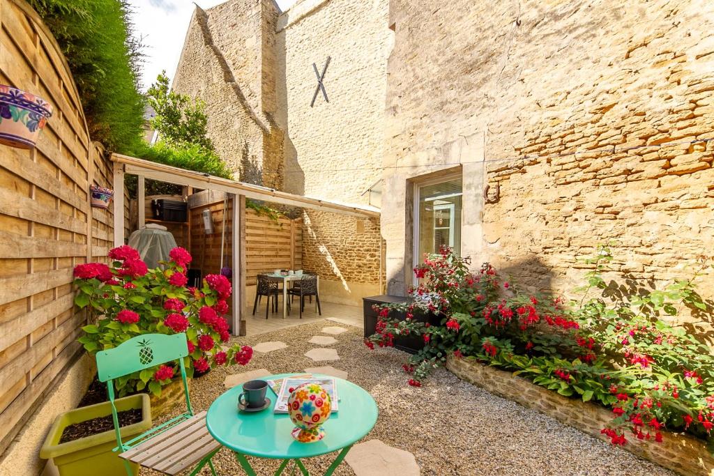 een patio met een tafel en bloemen en een gebouw bij La Rochambelle - Charmante maison de pêcheurs in Bernières-sur-Mer