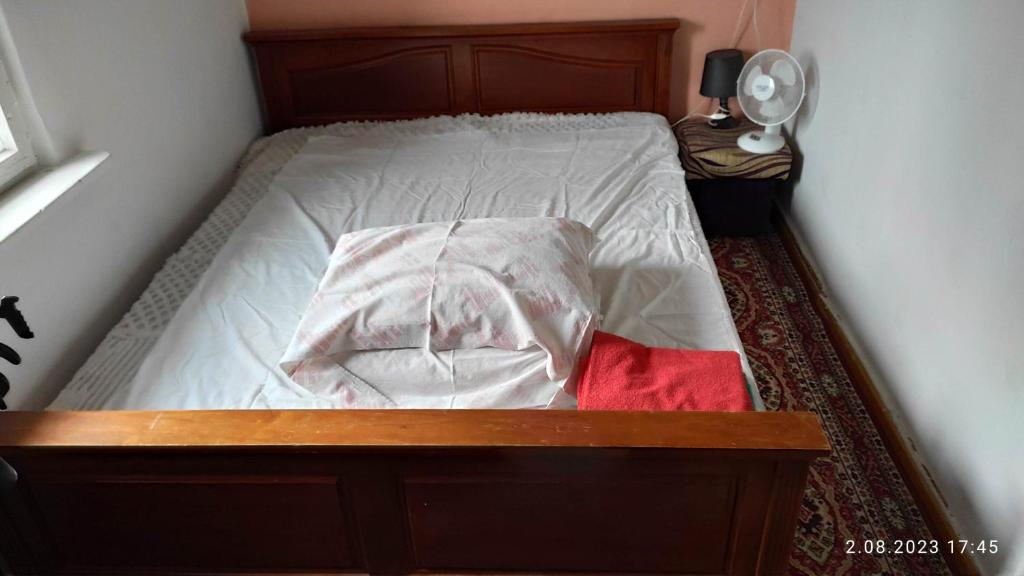 a bedroom with a bed with white sheets and a fan at Plaża Ustka in Ustka