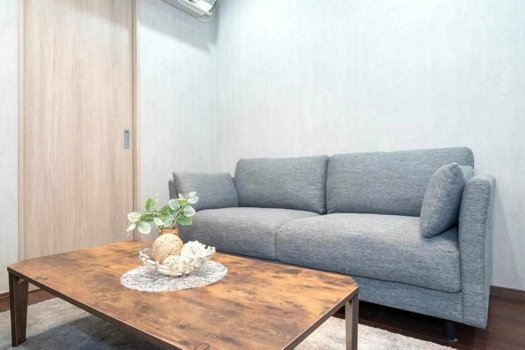 Una sala de estar con un sofá y una mesa de café. en Kyobashi house Entire house for rentー 京橋一軒家完全貸切, en Osaka