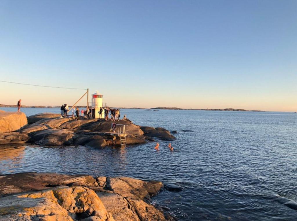 un groupe de personnes dans l'eau près d'un phare dans l'établissement BB Snäckan Hönö, à Hönö