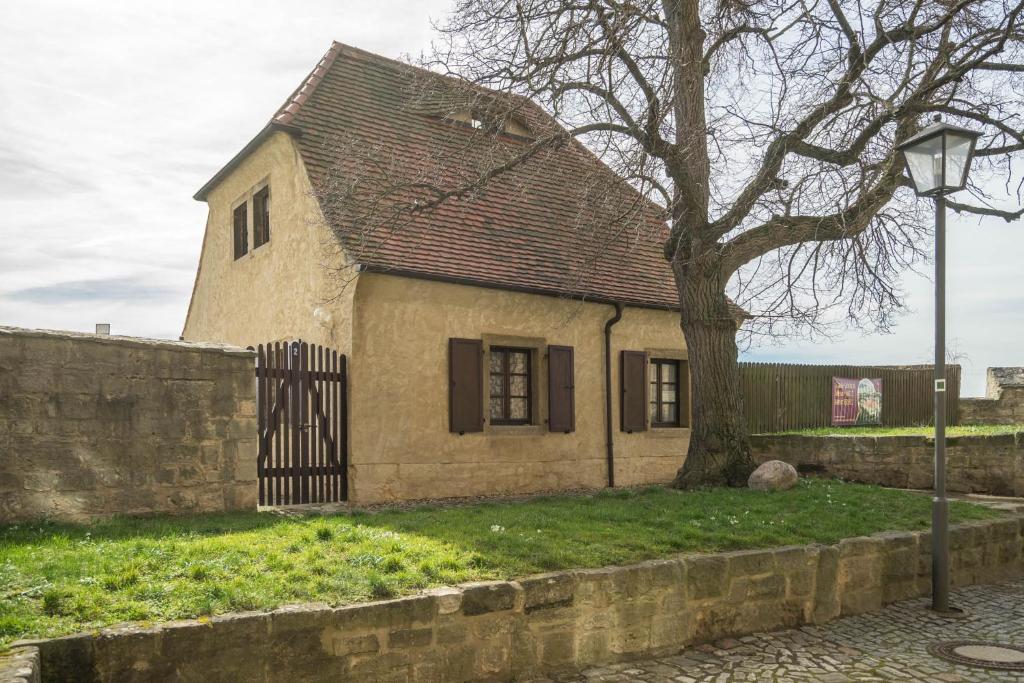 une vieille maison avec un arbre à côté d'un mur dans l'établissement Jägerhaus auf Schloss Neuenburg, à Freyburg