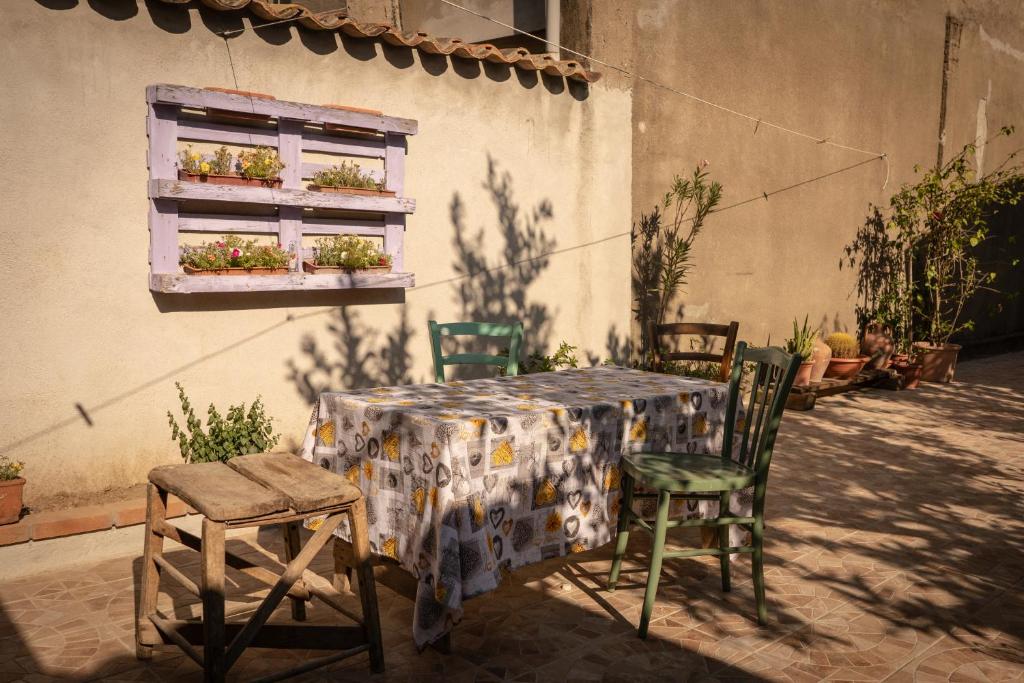 einen Tisch und Stühle sowie ein Fenster mit Pflanzen in der Unterkunft Sa Domu de Ladiri - GuestHouse con bagno privato e giardino in Musei