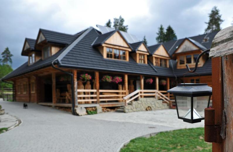 a large wooden house with a black roof at Folwark Toporzysko in Jordanów