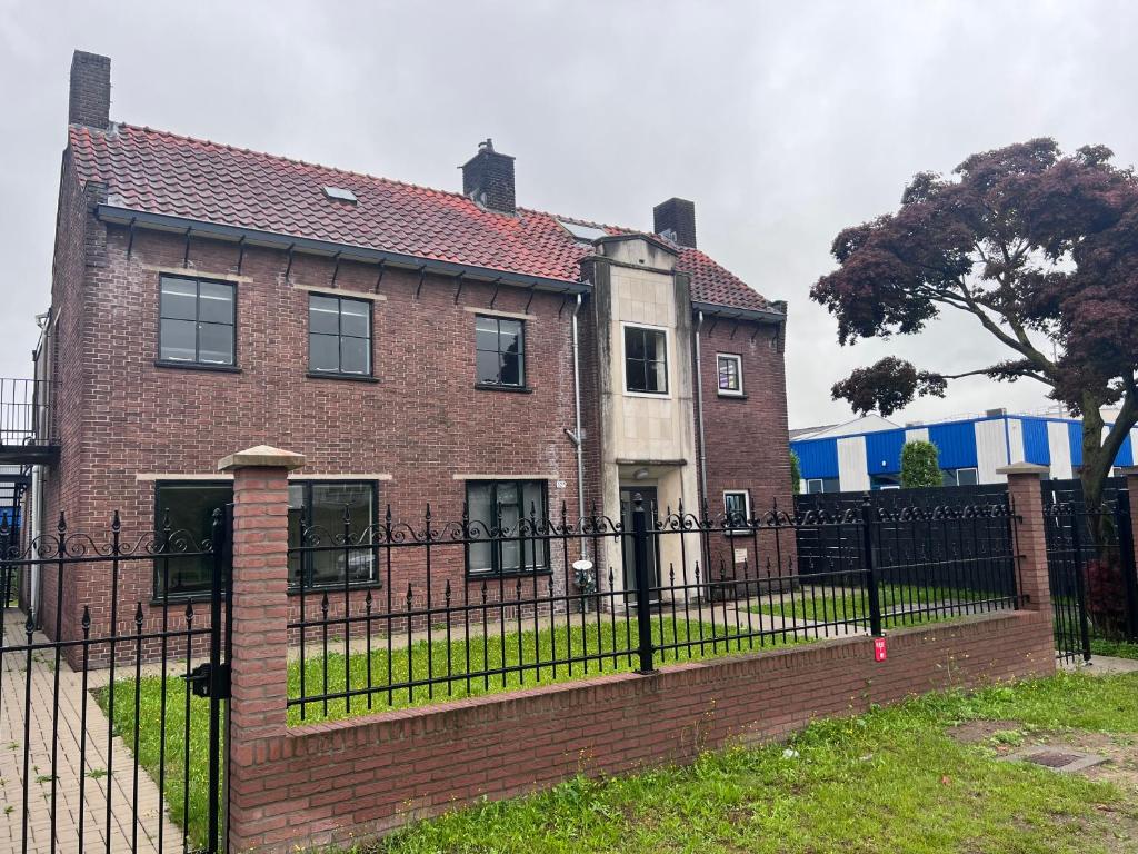 een groot bakstenen huis met een zwart hek bij Kess Maison, Gehele villa met dakterras Enschede in Enschede