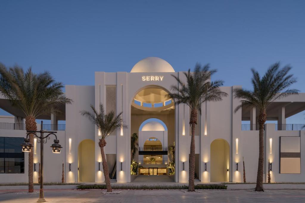 a building with palm trees in front of it at Serry Beach Resort in Hurghada