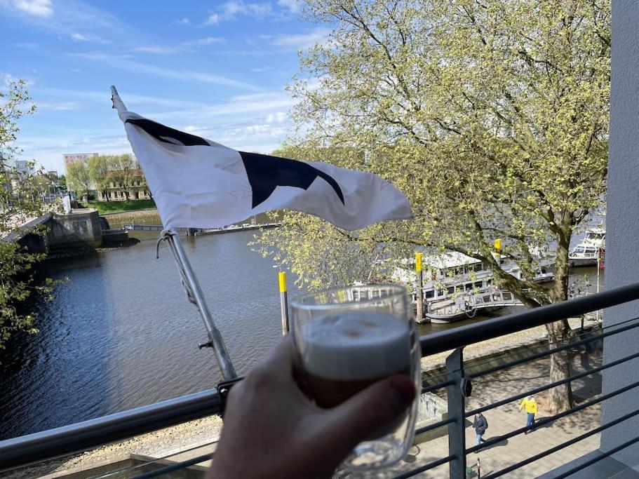 a person holding a drink in front of a flag at Bremen Weser Best View Apartment in Bremen
