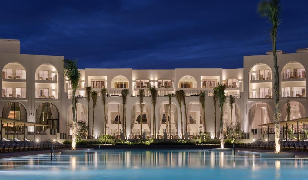 a large building with palm trees in front of it at Serry Beach Resort in Hurghada