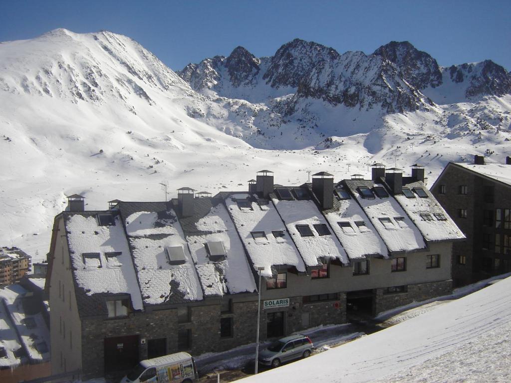 un edificio cubierto de nieve frente a una montaña en Appartements Solaris, en Pas de la Casa