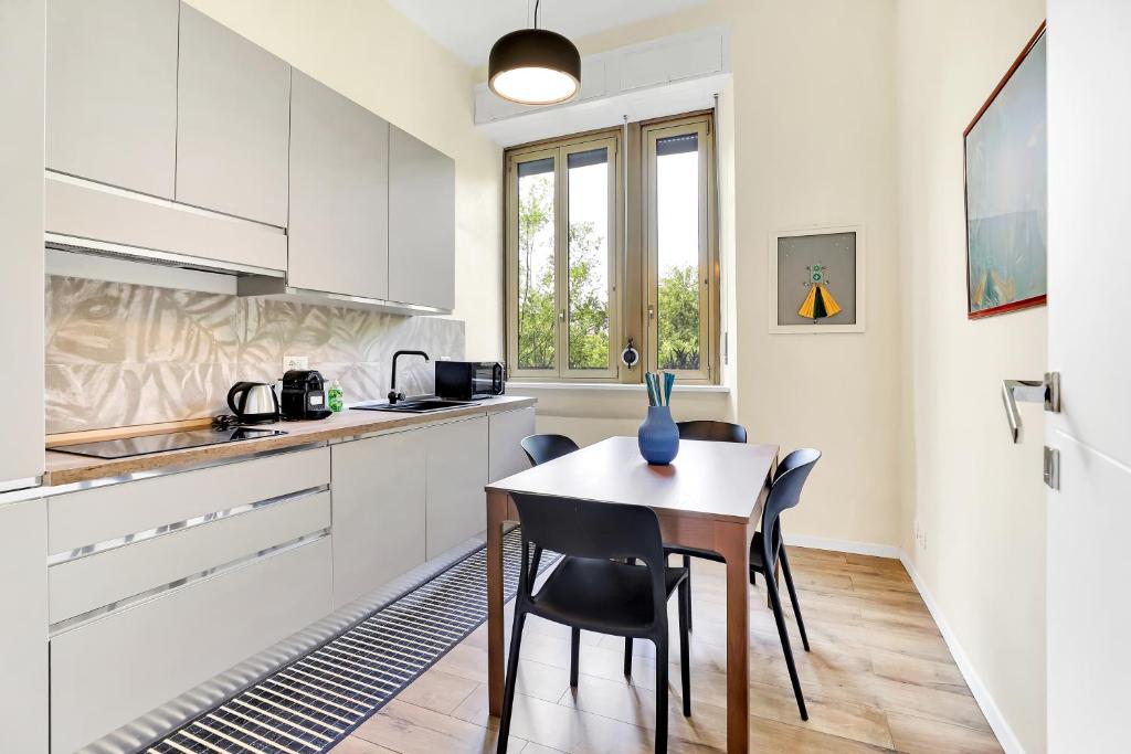 cocina con armarios blancos, mesa y sillas en Appartamento Napoli 25 - Affitti Brevi Italia, en Milán