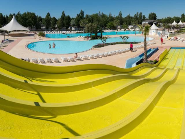 un toboggan jaune dans un complexe avec piscine dans l'établissement BUNGALOW LUXE MAZET ROYAL carabasse Vias plage ACCES proximité PISCINE, à Vias