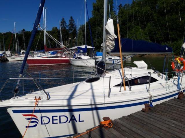 a white boat docked at a dock with other boats at Jacht Dedal Viva 700 in Polańczyk