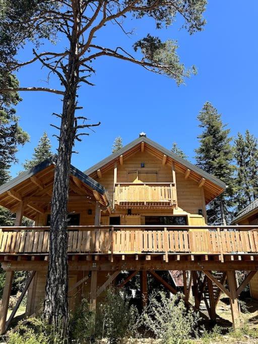 a large wooden house on a bridge with a tree at Superbe Chalet Cabane Chabanon in Selonnet