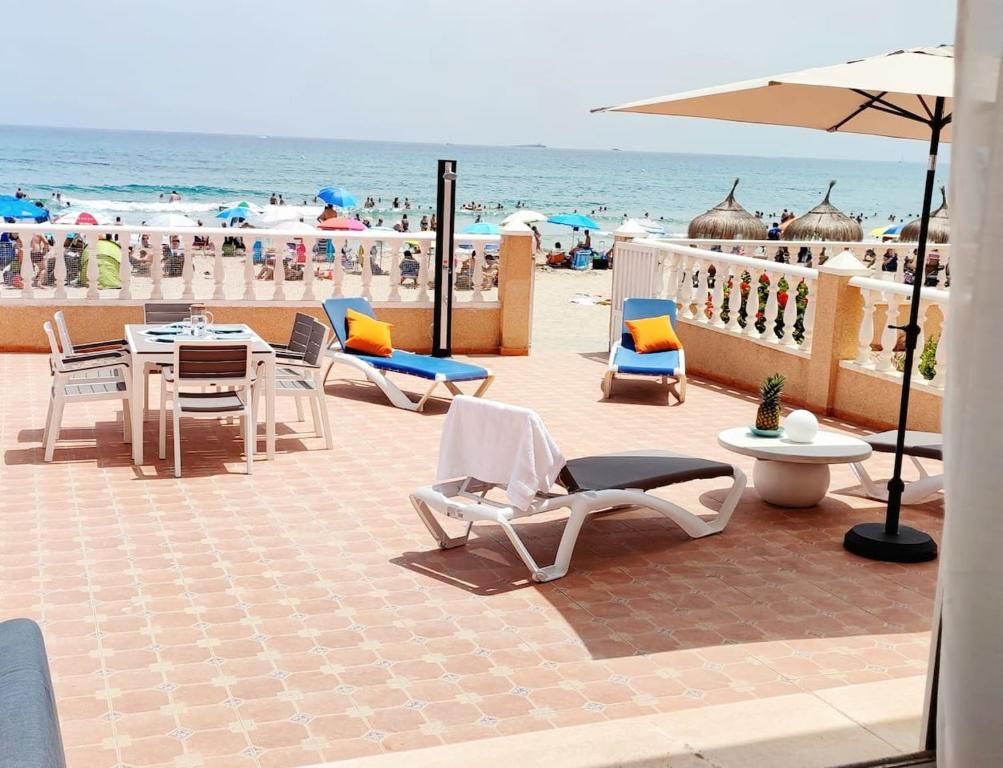 un patio con sillas y mesas y la playa en duplex sobre la playa, en La Manga del Mar Menor
