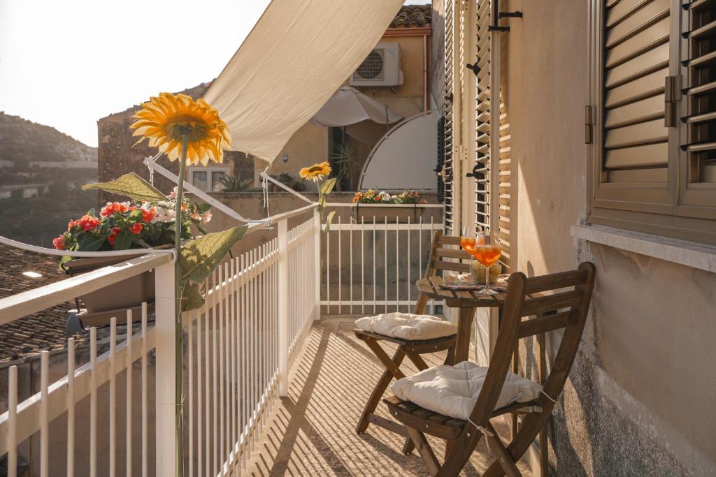 een balkon met 2 stoelen en een tafel met een zonnebloem bij Il Girasole in Modica